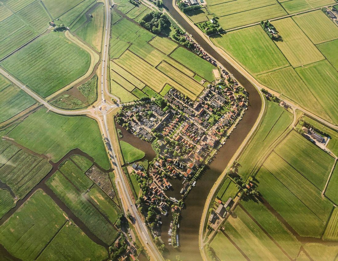 Luchtfoto van een dorp aan een rivier tussen weilanden